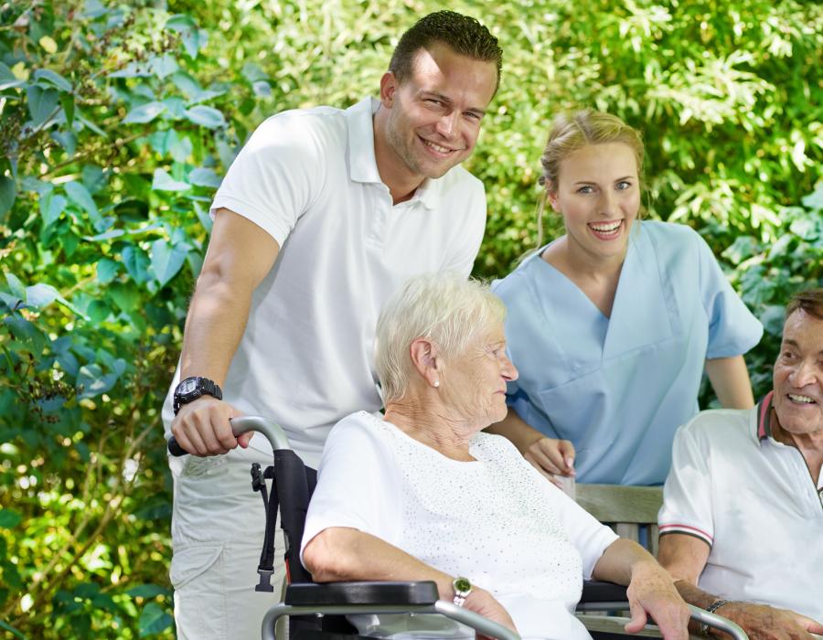 Ein Altenpfleger mit glücklichen Senioren im Park