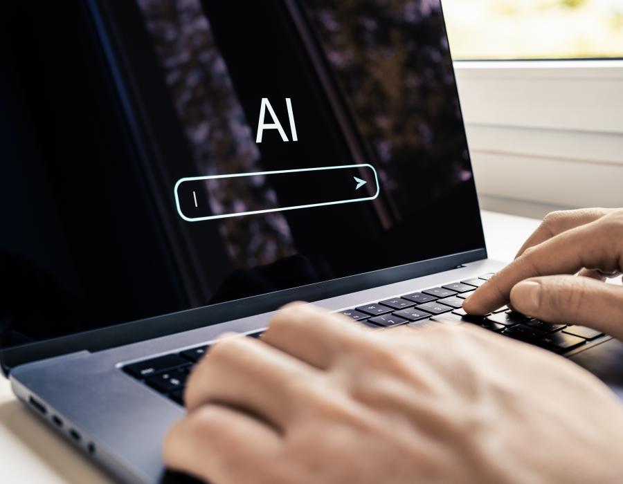 Hand an Laptop schreibt mit KI Chatbot